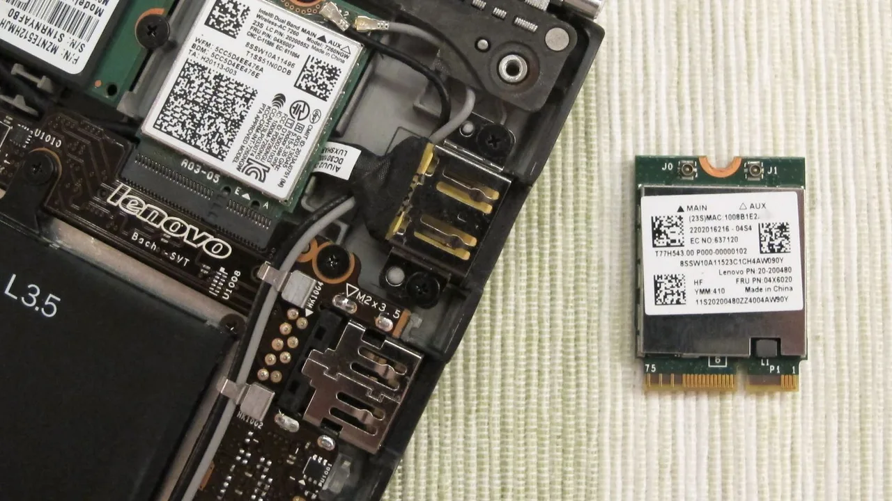 An opened Lenovo laptop with one Wi-Fi module installed and another beside it