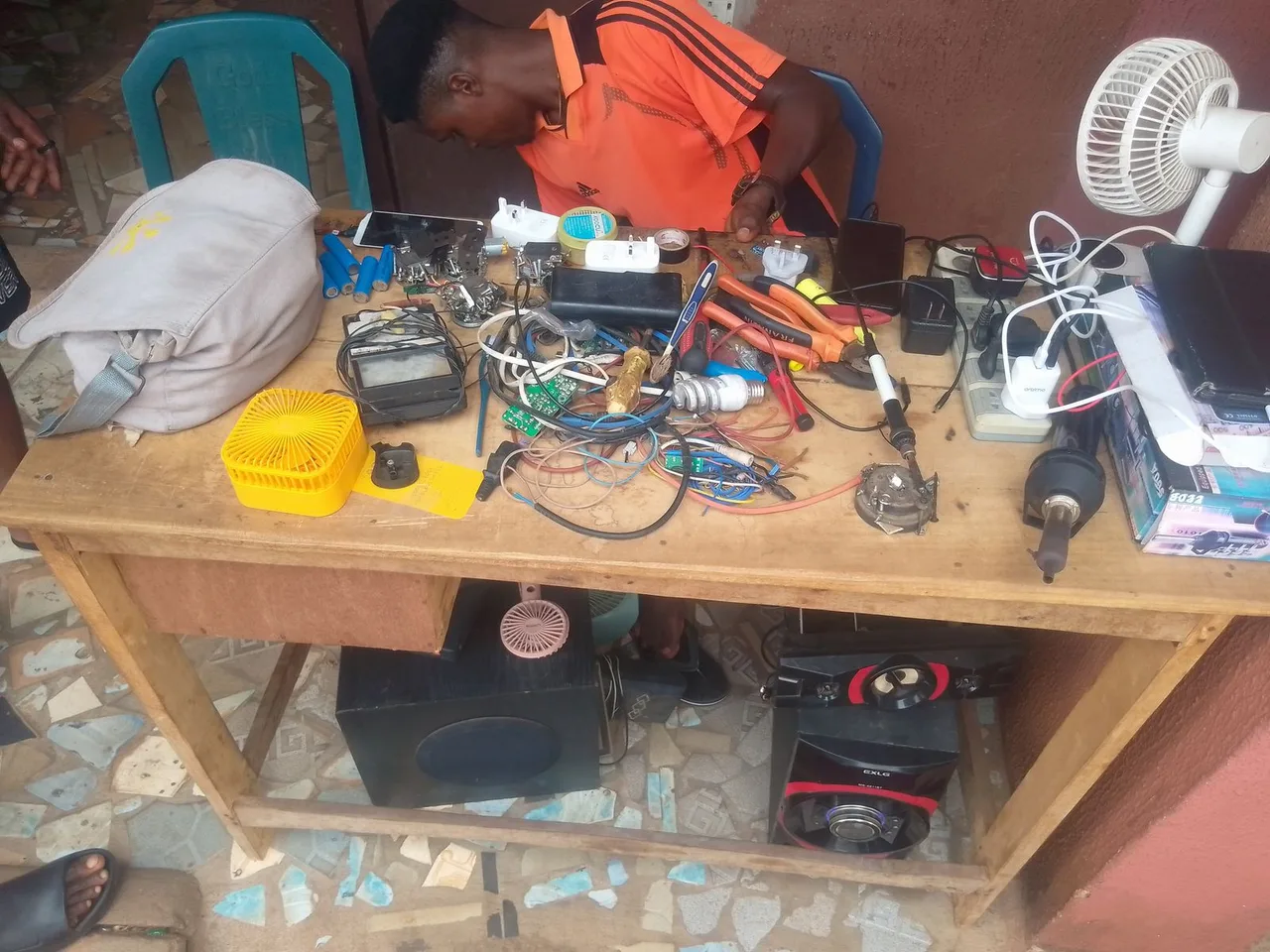 A technician working among electronic devices, tools, and components at a repair bench