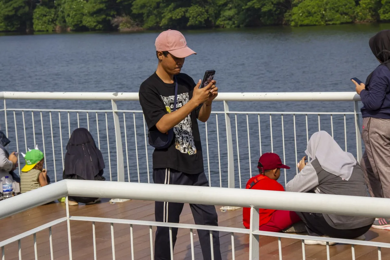 A man using a smartphone near a lake